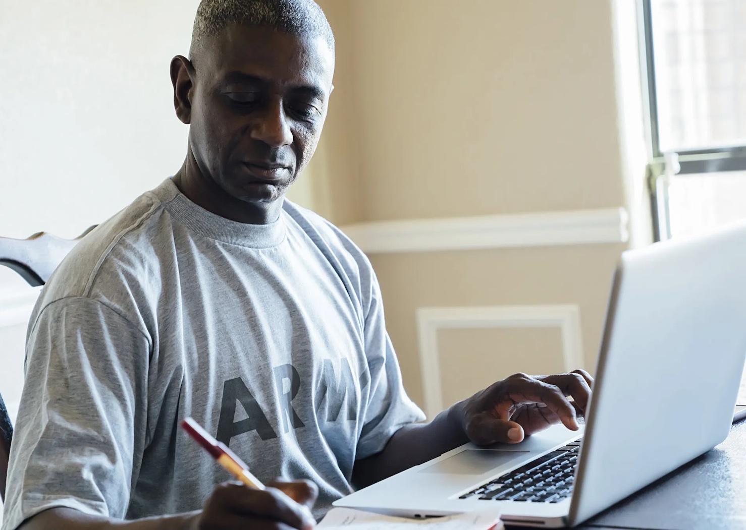 army veteran types on laptop while looking at paper